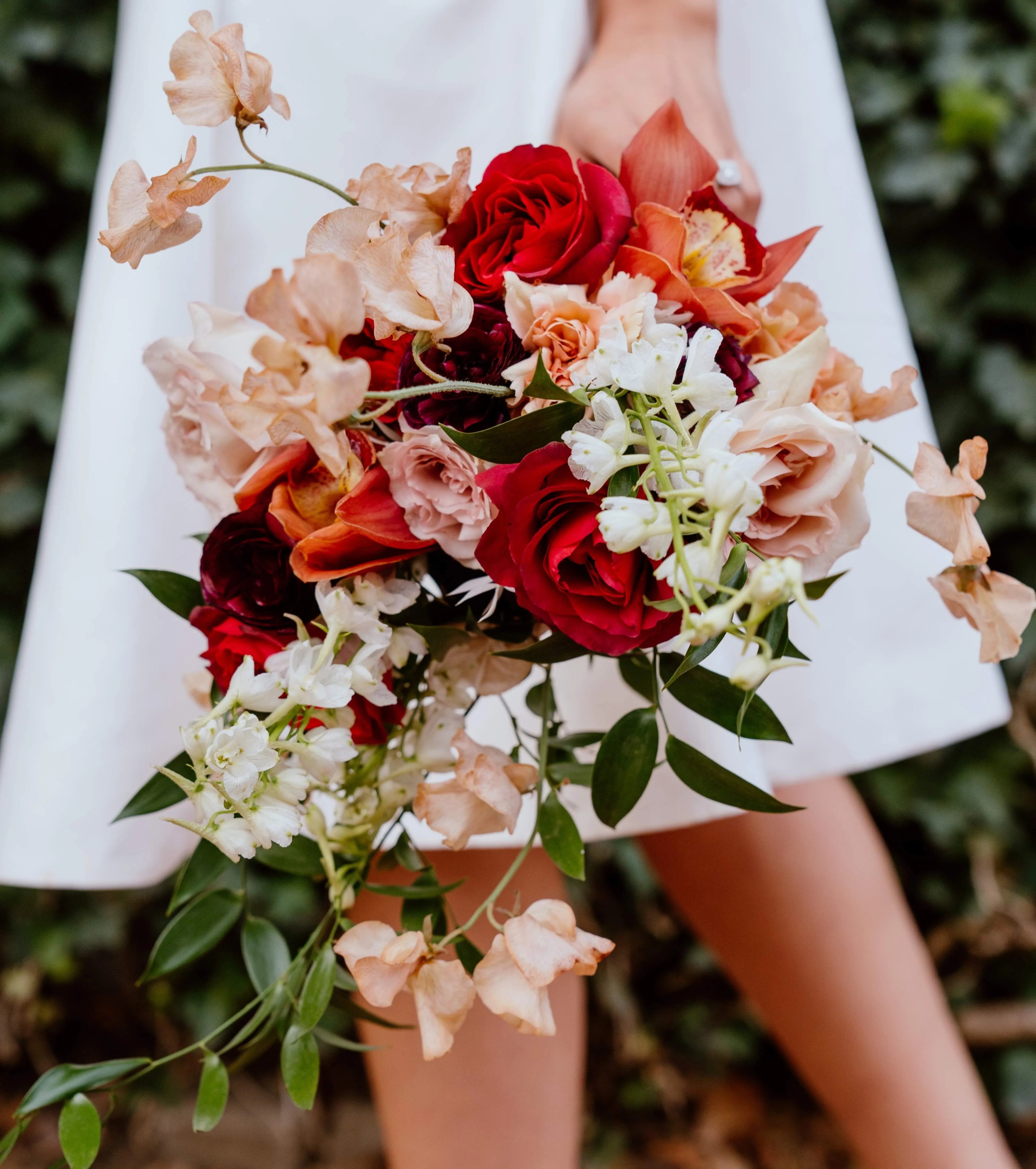 a bride holding a bouquet of red and white flowers